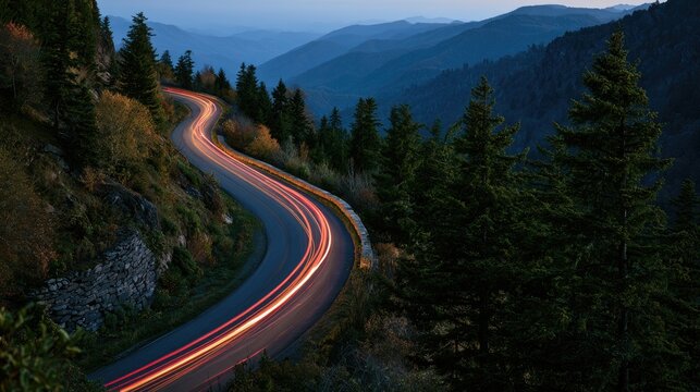 Winding mountain road at dusk, light trails from vehicles, forested slopes
