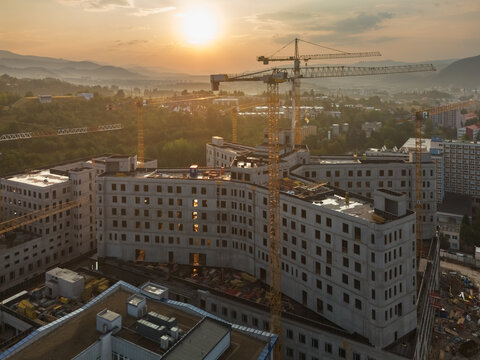 Aerial view of the construction site of the new F. D. Roosevelt University Hospital featuring multiple tower cranes and concrete structures at sunset in Banska Bystrica, Slovakia.
