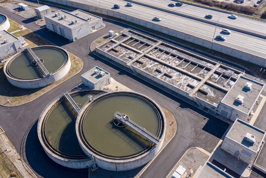 Aerial drone view of a wastewater treatment plant with circular clarifiers and aeration basins