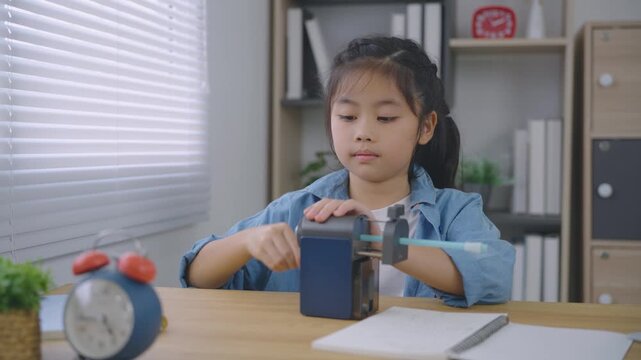 Young girl using pencil sharpener at desk focused on schoolwork in cozy room with natural light and organized shelves
