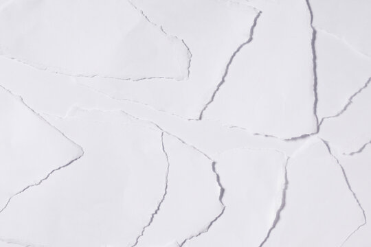 Pile of torn white paper scraps arranged on a clean white background with rough ripped edges.