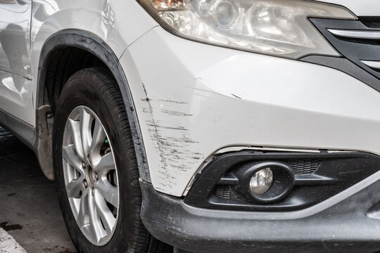 scratched and damaged front bumper on white car after accident