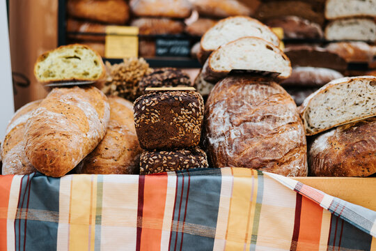 A market stall is filled with various types of artisanal breads, including loaves and rolls.