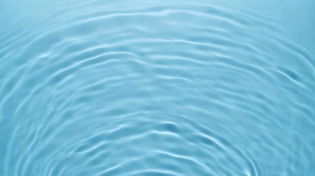 Serene cinematic macro shot of soft blue water surface showing concentric circular ripples and fluid wave patterns