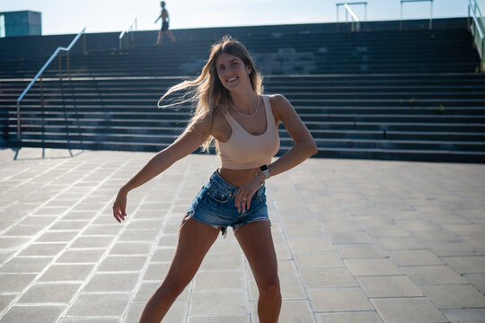 Smiling woman dancing outdoors on urban steps