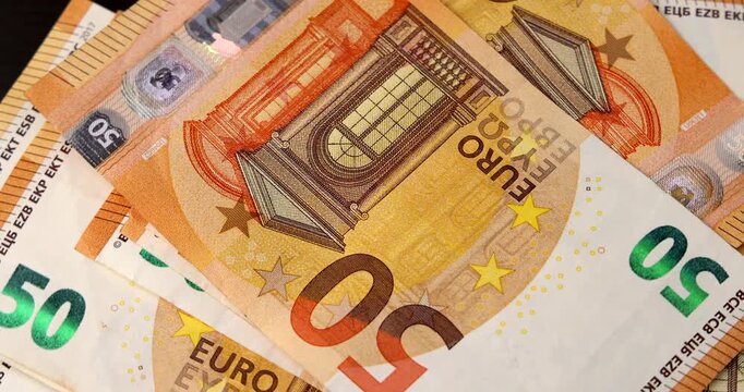 Fifty euro cash bills placed randomly are spinning smoothly in a top down horizontal view, highlighting financial success and monetary value concepts.