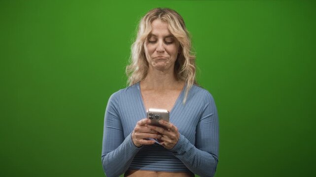 Middle aged woman texting on smartphone, hands visible and holding device, slight smirk while looking down at screen in studio; thoughtful reflection.