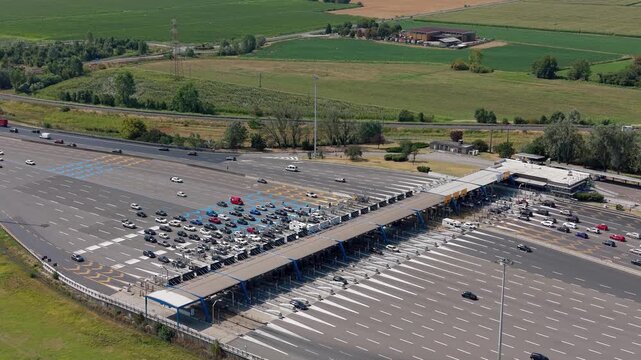 Drone perspective of Barriera Milano Sud on the A1 motorway near Melegnano, Italy, with toll facilities and flowing road traffic.