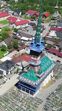 Drone view of the Merry Cemetery, a famous open air museum in Sapanta, Maramure. Colorful tombstones and a traditional wooden church. With more than 800 colorful oak wood crosses