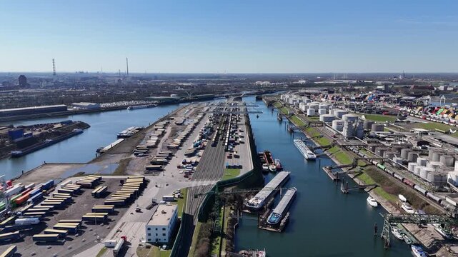 Wide backward drone flight revealing tank unloading berths container terminals silos and the large scale of Duisport.