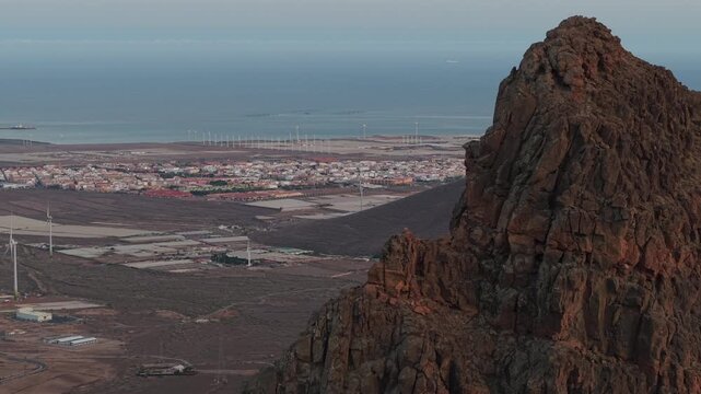 Aerial view of the Roque Aguayro natural monument with the coastal town and wind farm in the background on Gran Canaria island