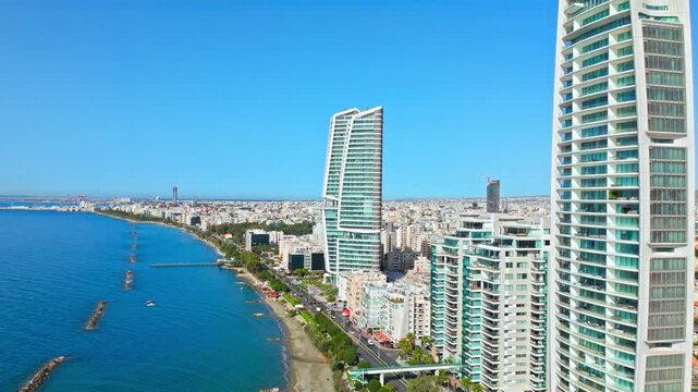 Aerial view of Limassol seafront in Cyprus. A tall modern tower, beachfront promenade and blue Mediterranean water create a scenic coastal skyline.