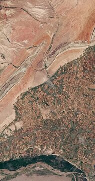 Top shot on agricultural landscape in dry area. Camera is zooming in, rotating counterclockwise. Vertical video. Animation based on image by NASA