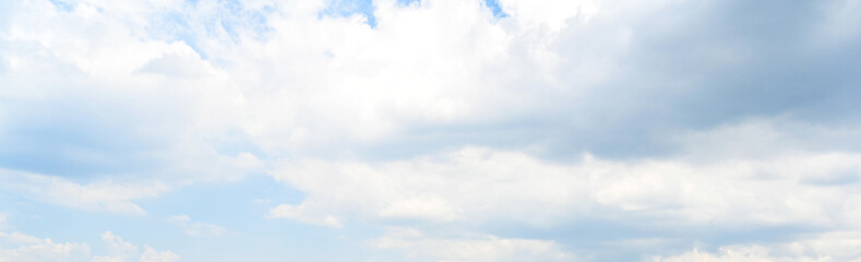 Obraz premium Wide panoramic view of bright blue sky with soft white cumulus clouds, natural overcast light, cloudy daytime atmosphere texture background for design header banner.
