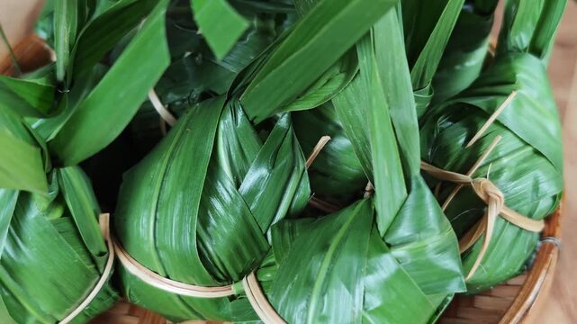 traditional sticky rice dumpling wrapped in green leaves, tied with bamboo string
