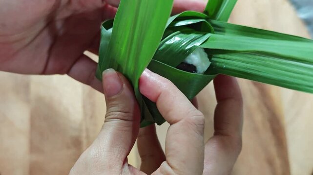 traditional sticky rice dumpling wrapped in green leaves, tied with bamboo string
