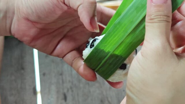 traditional sticky rice dumpling wrapped in green leaves, tied with bamboo string
