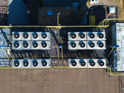 Aerial view of data center HVAC thermal management cooling fans on a rooftop with industrial metal grating and safety railings in Andover, England, United Kingdom.
