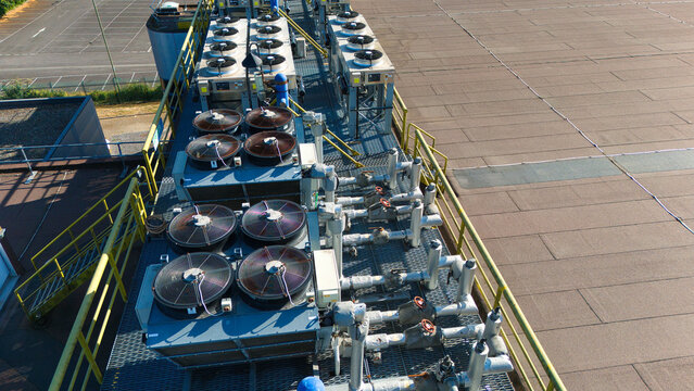 Aerial view of data center HVAC thermal management and cooling fans with industrial piping and metal grating on a rooftop in Andover, England, United Kingdom.