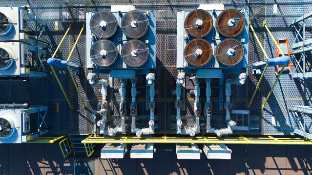 Aerial view of data center HVAC thermal management and cooling fans with industrial piping and metal grating on a rooftop in Andover, England, United Kingdom.