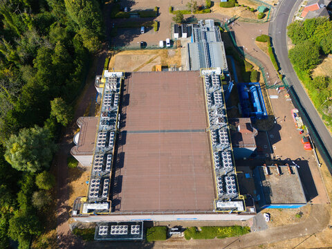 Aerial view of a data center roof featuring extensive HVAC thermal management systems and rows of industrial cooling fans, situated in a suburban area in Andover, England, United Kingdom.