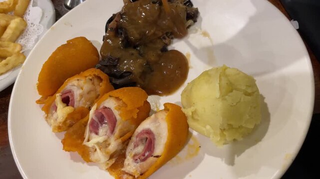 Restaurant Main Course Meal: Savory Steak, Chicken Roulade, Mashed Potatoes, and Fried Plantains. Gourmet Dinner Plate for Menu Design