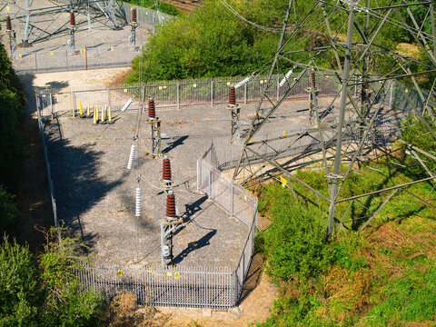 Aerial view of high voltage power lines and electrical infrastructure at a substation surrounded by green vegetation in Nursling, England, United Kingdom.