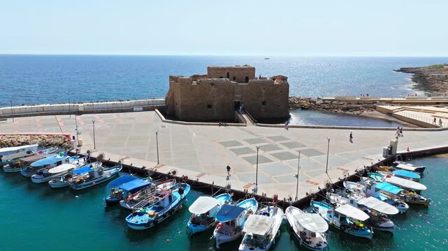Aerial view of Paphos Castle in Cyprus. The historic stone fortress stands beside the harbour, promenade and blue Mediterranean Sea.