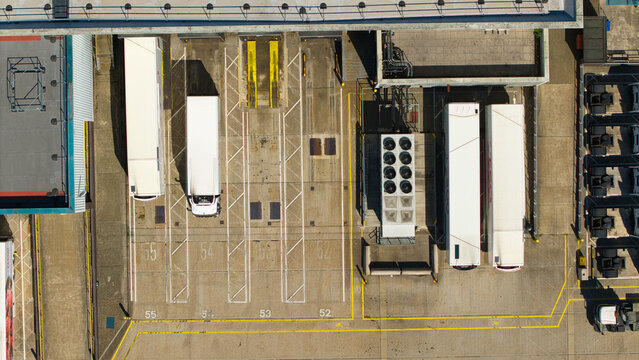 Aerial view of Nursling Industrial Estate showing semi-truck trailers parked in numbered loading bays on concrete pavement in Nursling, England, United Kingdom.