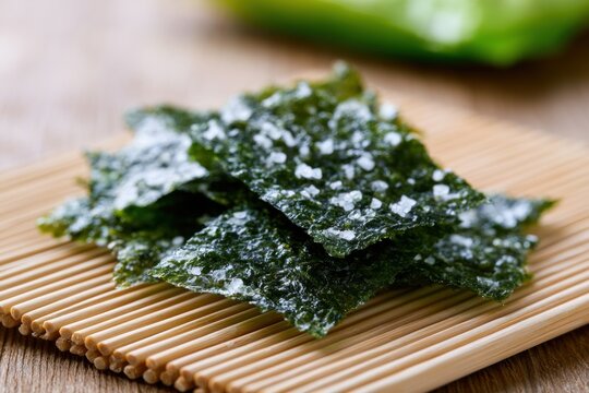 Crispy thin seaweed sheets seasoned with salt flakes resting on a natural bamboo mat surface