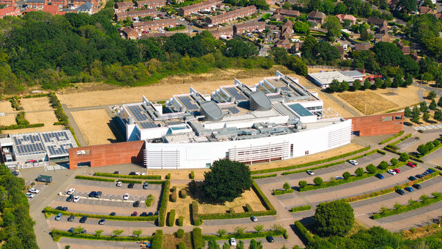 Aerial view of the Nursling Industrial Estate featuring a large modern office building with solar panels, surrounded by parking lots and green spaces in Nursling, England, United Kingdom.