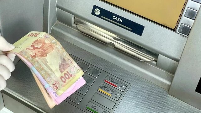 Female hands take money from an ATM machine with close up of woman receiving cash banknotes from automated teller in 4K Ultra HD footage
