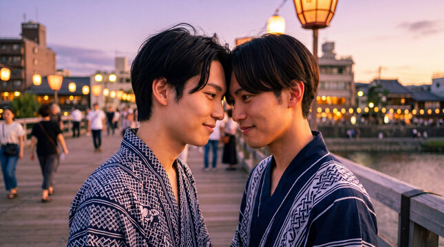 夕暮れの川辺で額を寄せ合う浴衣姿の男性カップル | 夕焼け色