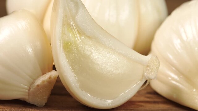Macro shot of fresh young garlic cloves slowly moving under studio lighting.