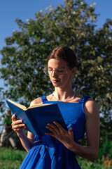Fototapeta premium Girl with book on park bench. Conscious gadget break. Harmony with nature and literature. Slow living at its best. Seasonal ritual of summer reading outdoors. Book lovers day