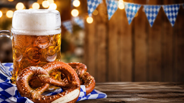 Background for Oktoberfest promotions and pub ads. Beer mug and pretzel on a wooden table.