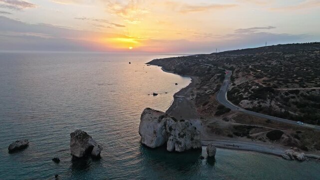 Drone view of Aphrodite&rsquo;s Rock at golden sunset in Cyprus. The large sea stack, rocky beach and golden Mediterranean water create a peaceful coastal scene.