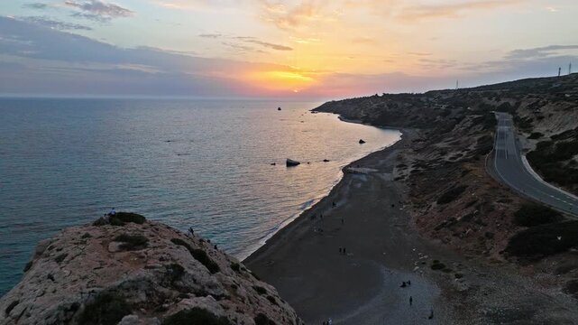 Drone view over Aphrodite&rsquo;s Rock at golden sunset in Cyprus. Warm evening light, rugged cliffs and calm water create a scenic romantic landscape..