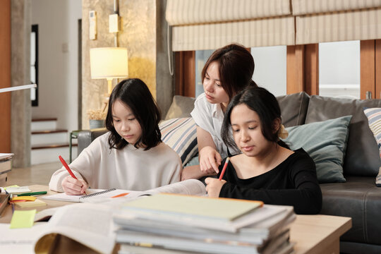 Three Asian teenage girls learning tutorials at home together, reading textbooks, writing notes, self-tutorial exams, preparing school homework, Homeschooling study, knowledge education lifestyle.