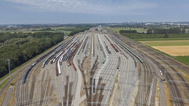 Aerial view of the Kijfhoek marshalling yard with numerous parallel railway tracks and freight trains surrounded by green fields in Zwijndrecht, South Holland, Netherlands.