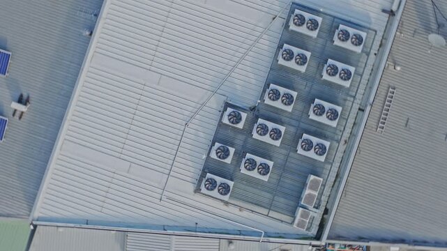 Drone footage captures a data center rooftop lined with industrial HVAC units and metallic panels, featuring clear geometric lines, even lighting, and crisp overhead composition for technology themes.