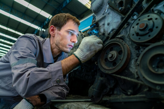 Male auto mechanic technician repairing car engine parts in industrial garage workshop warehouse, worker working mechanical  automotive engineering inspection and vehicle maintenance service facility