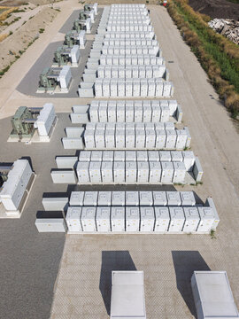 Aerial view of a large-scale battery energy storage system with rows of white container units and electrical transformers on a gravel site in Waddinxveen, South Holland, Netherlands.