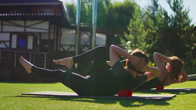 Elderly women practicing Pilates core exercises on yoga mats outdoors in slow motion, focusing on fitness, flexibility, balance, and healthy active aging together
