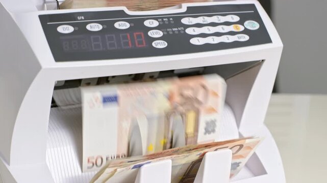 Female hand feeding fifty euro banknotes into the automated money counter machine with cash bills shuffling through it in 4K Ultra HD footage
