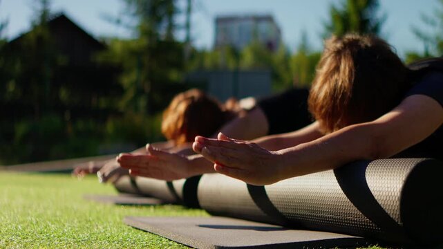 Elderly women practicing slow motion Pilates together outdoors on a sunny day, focusing on mindful movement, stability, strength and graceful functional fitness