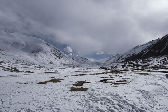 View of the snow-covered mountainous landscape of the Ladakh horizon under a cloudy sky in Leh, Ladakh, India.