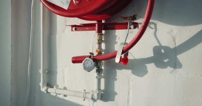 Building, safety and fire hose reel on wall for protection, compliance and emergency access. Pipe, firefighting equipment and outdoor installation for hazard prevention, water supply and regulations