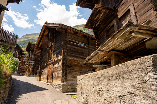 Traditional historic wooden alpine chalet architecture in the scenic mountain village of Zermatt, Switzerland during a sunny summer day.