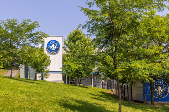 Montreal, Quebec, Canada. August 4, 2026. Exterior view of the CF Montreal soccer facility building framed by lush green trees.